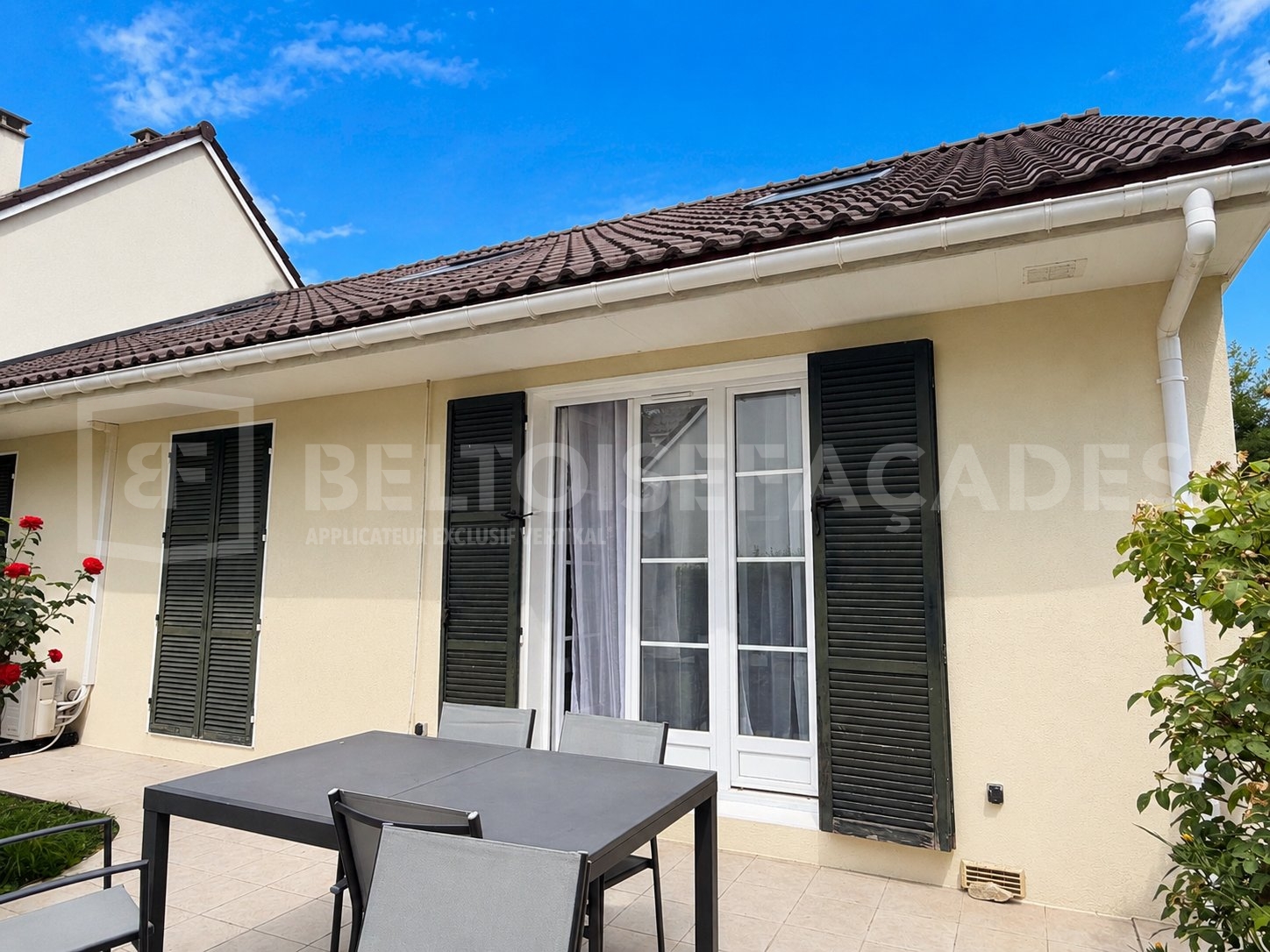Maison avec table extérieure et volets noirs par Beltoise Façades.