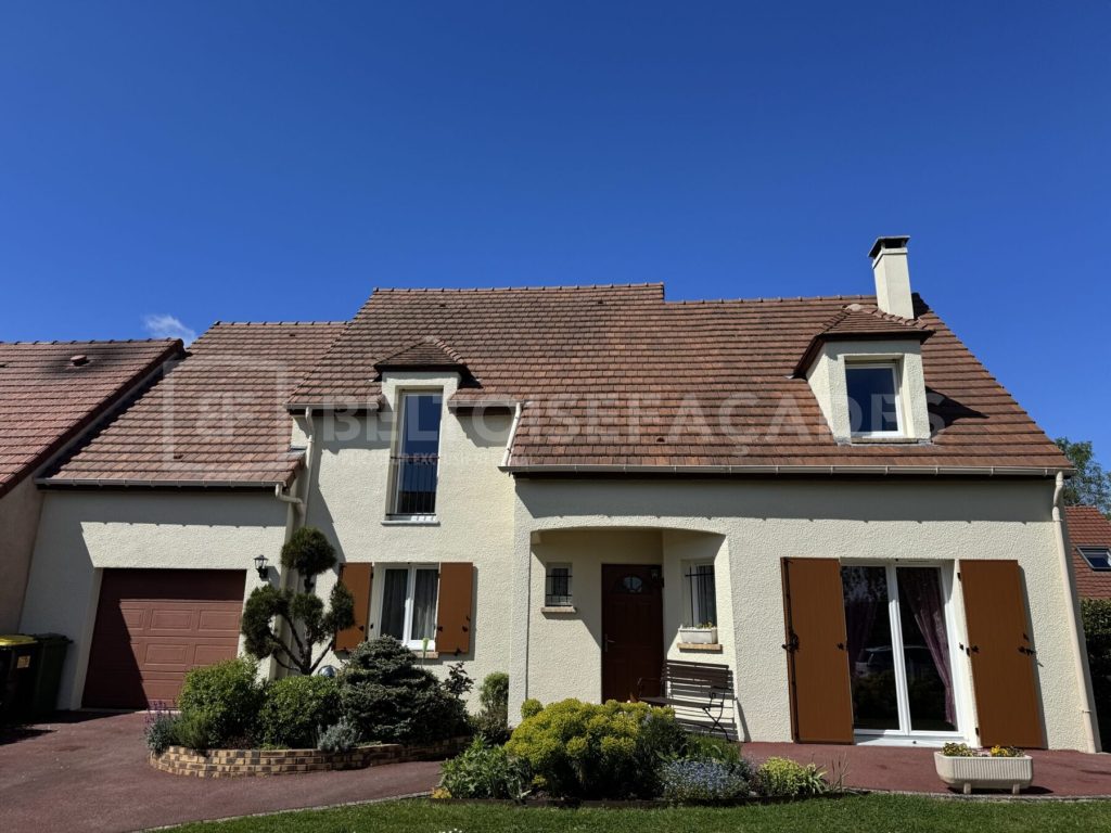 Maison rénovée par Beltoise Façades avec toit en tuiles et jardin fleuri.
